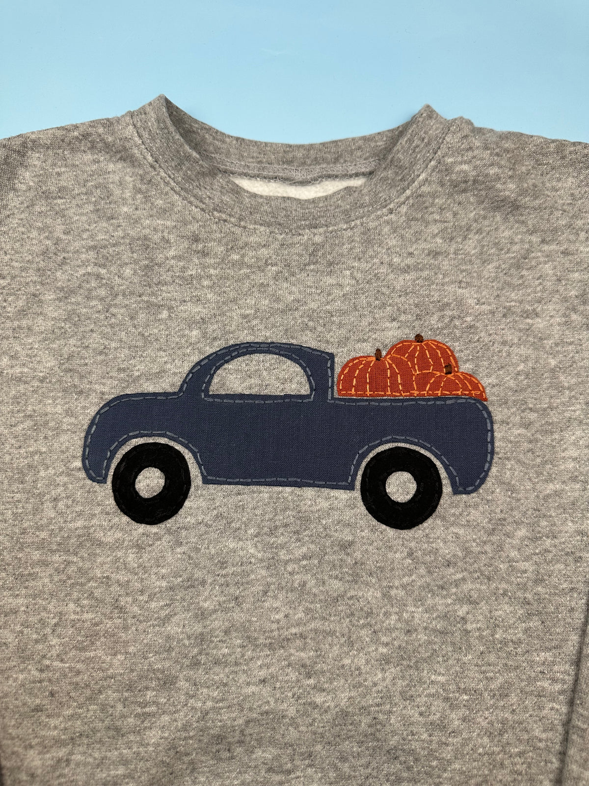Gray crewneck sweatshirt featuring applique navy truck and orange pumpkin cluster design