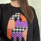 Black sweatshirt with patchwork applique ghost graphic, close-up