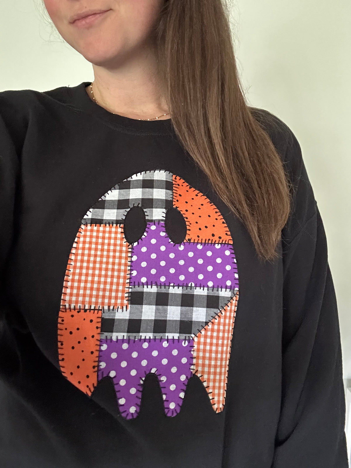 Black sweatshirt with patchwork applique ghost graphic, close-up