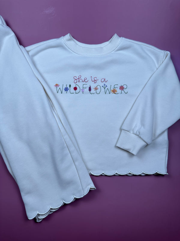 Light blue long-sleeve sweatshirt with crew neck and colorful wildflower text graphic