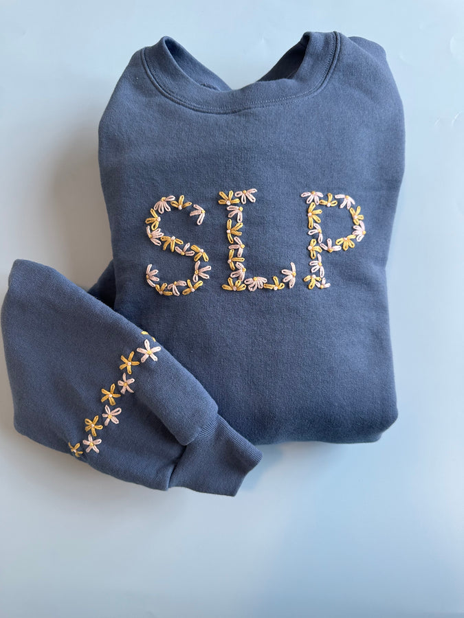 Dark blue sweatshirt with embroidered uppercase alphabet letters on chest and sleeve cuffs