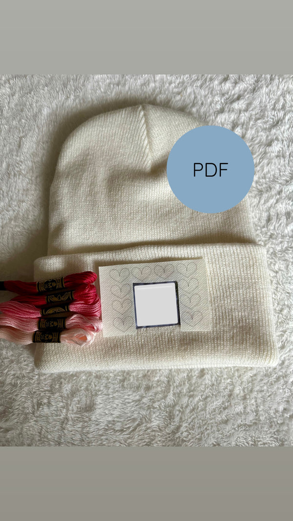 Cream beanie embroidery design with heart motif and small square placement guide