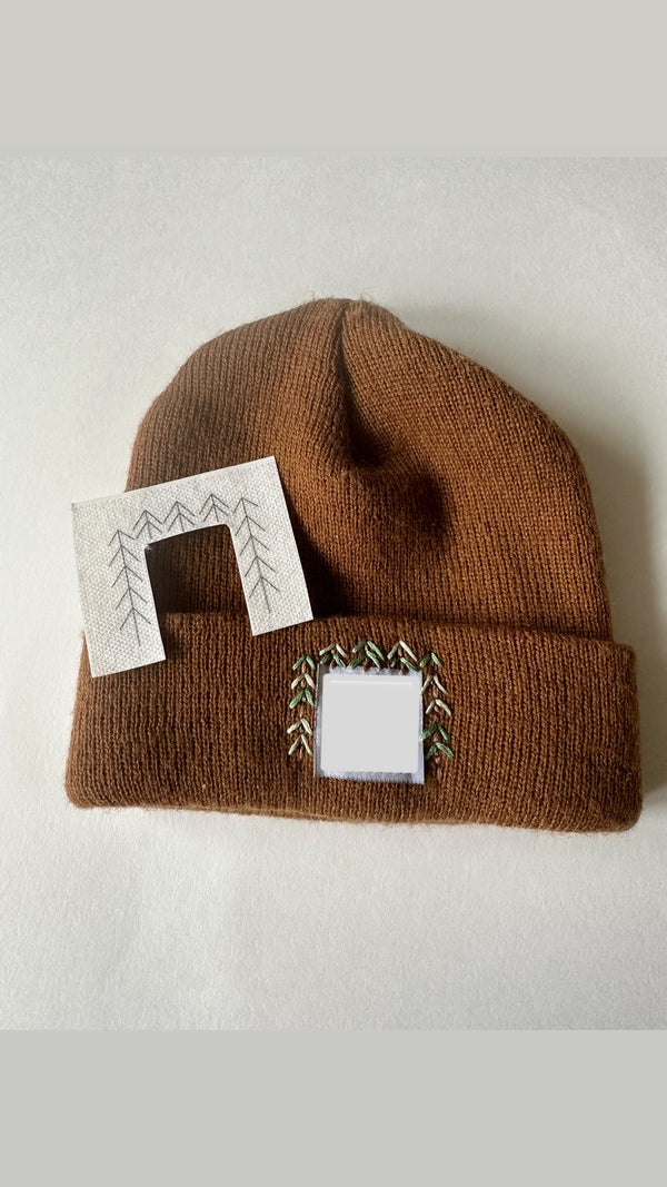 Brown knit beanie with square embroidered pine tree patch on the cuff